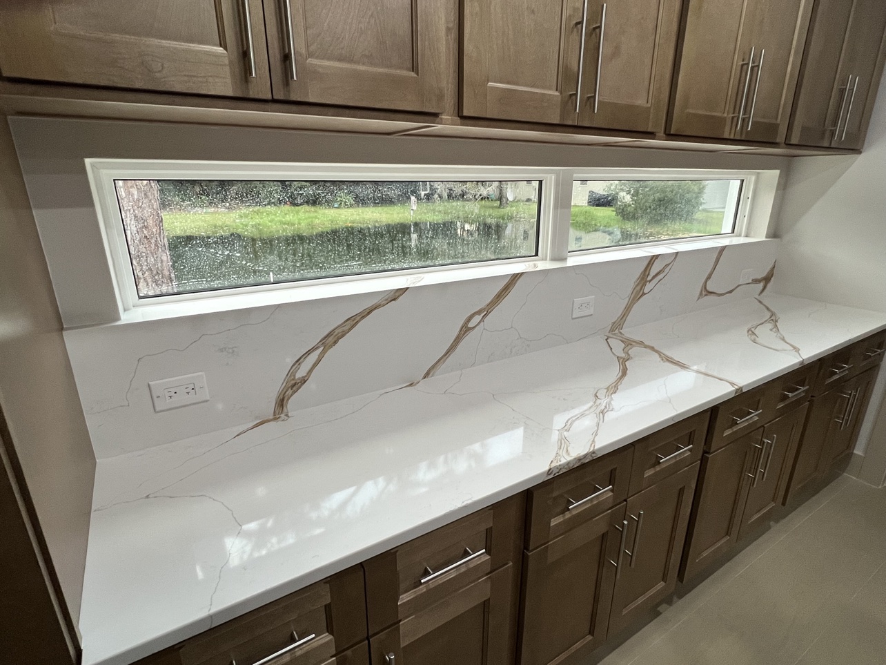 Finished quartz countertop with gold veining and full backsplash by All Surface Experts Co.